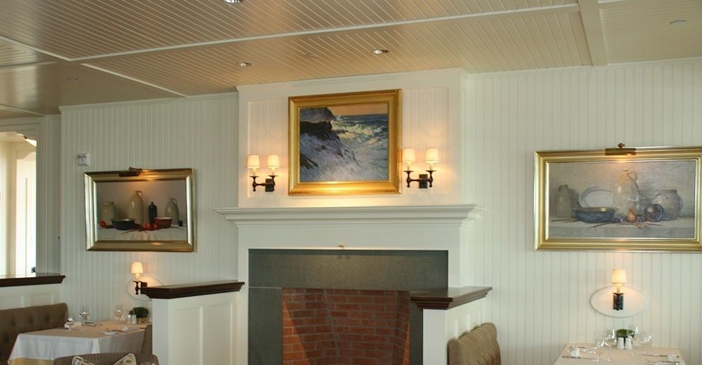 La salle à manger de l’Ocean House Hotel : lambris et plafond de planches blanches, foyer, tableaux encadrés d’or