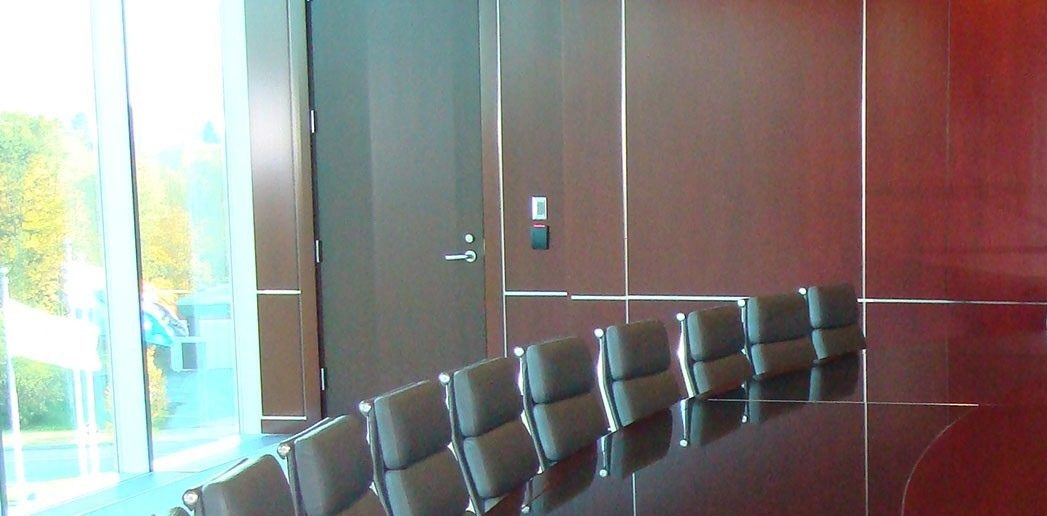 La salle du conseil du Service Credit Union à Portsmouth : panneaux de bois sombre à haut lustre, filets de métal, fauteuils de cuir