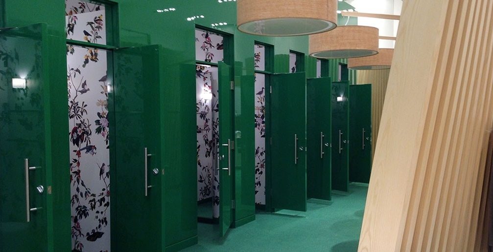 Les cabines d’essayage d’un magasin La Maison Simons : portes laquées vert à haut lustre, panneaux fleuris, colonne de frêne
